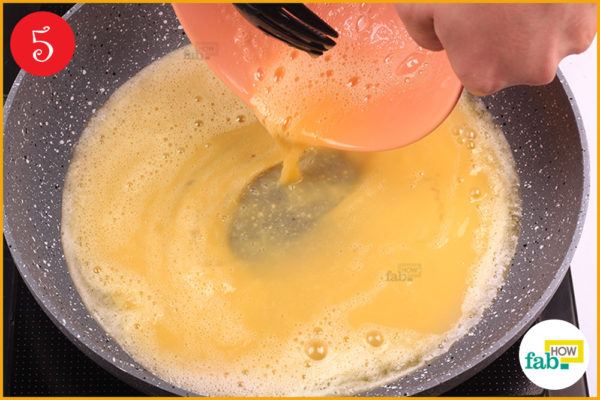 Pour beaten eggs into the pan