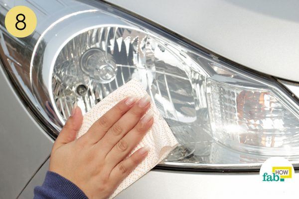 wipe car headlight with paper towel to clean it 